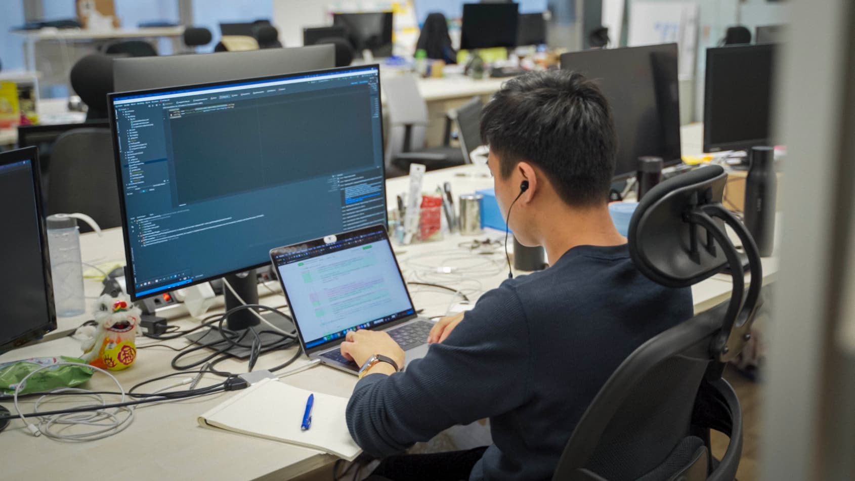 GovTechie, sitting at a desk with two screens, hard at work at GovTech office